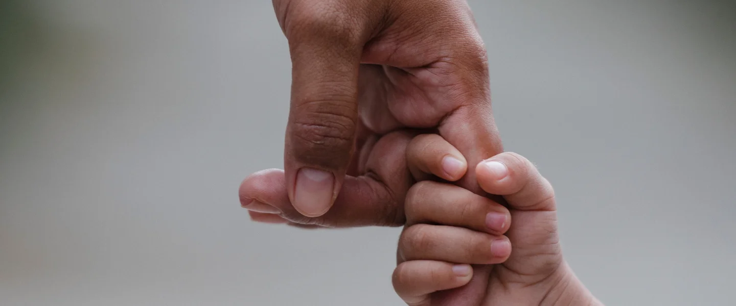Child holding adult finger